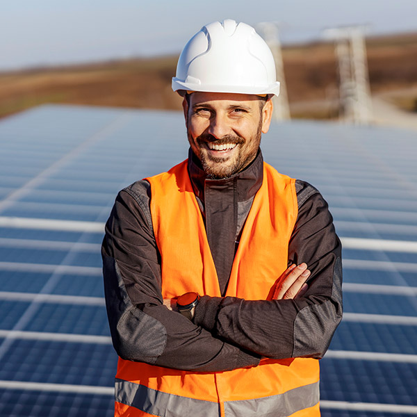 A man with a high-vis jacket and hard hat smiling at camera