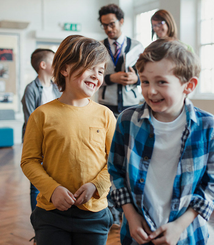 Two young boys laughing, looking as if they are in a school